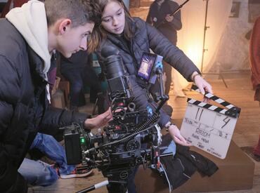 Young people using a camera to film a scene with directors claperboard 