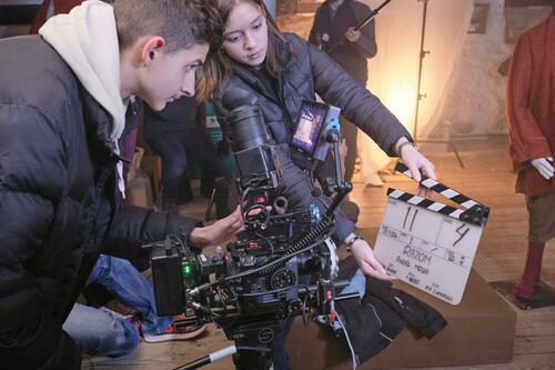 Young people using a camera to film a scene with directors claperboard 